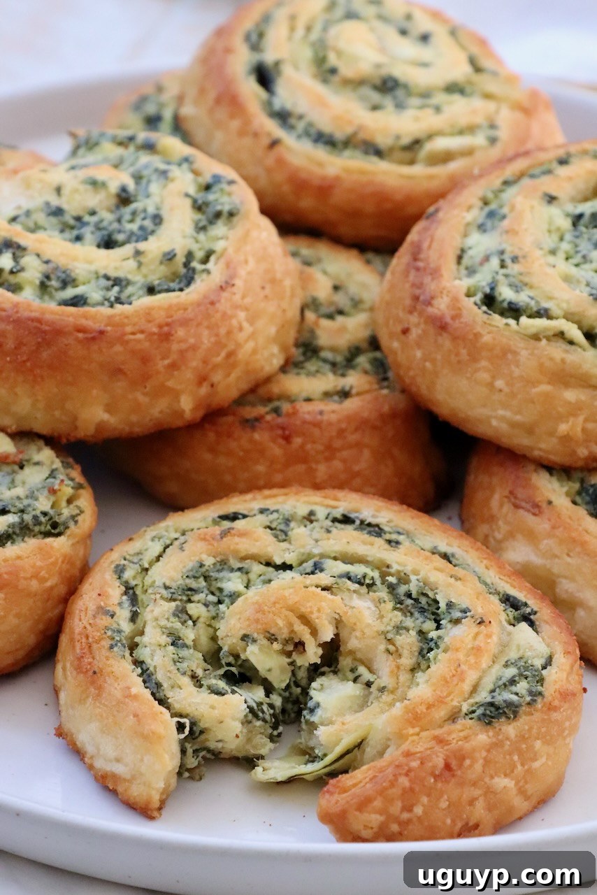 Spinach dip rolls stacked up on a plate, ready to be served as an appetizer.