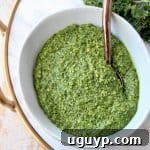 Kale pesto in white bowl with copper spoon