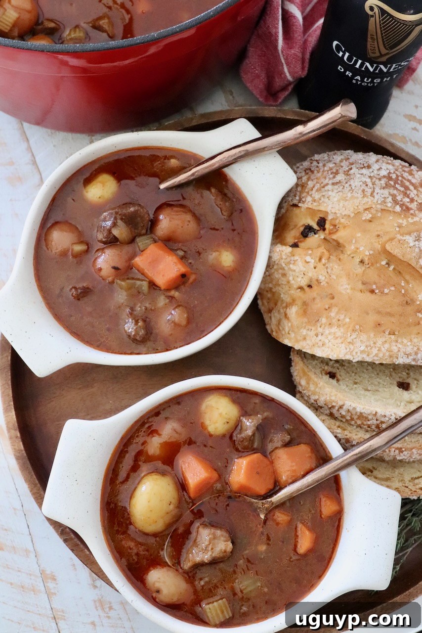 Two bowls of Irish stew with spoons, served with sliced bread on the side.