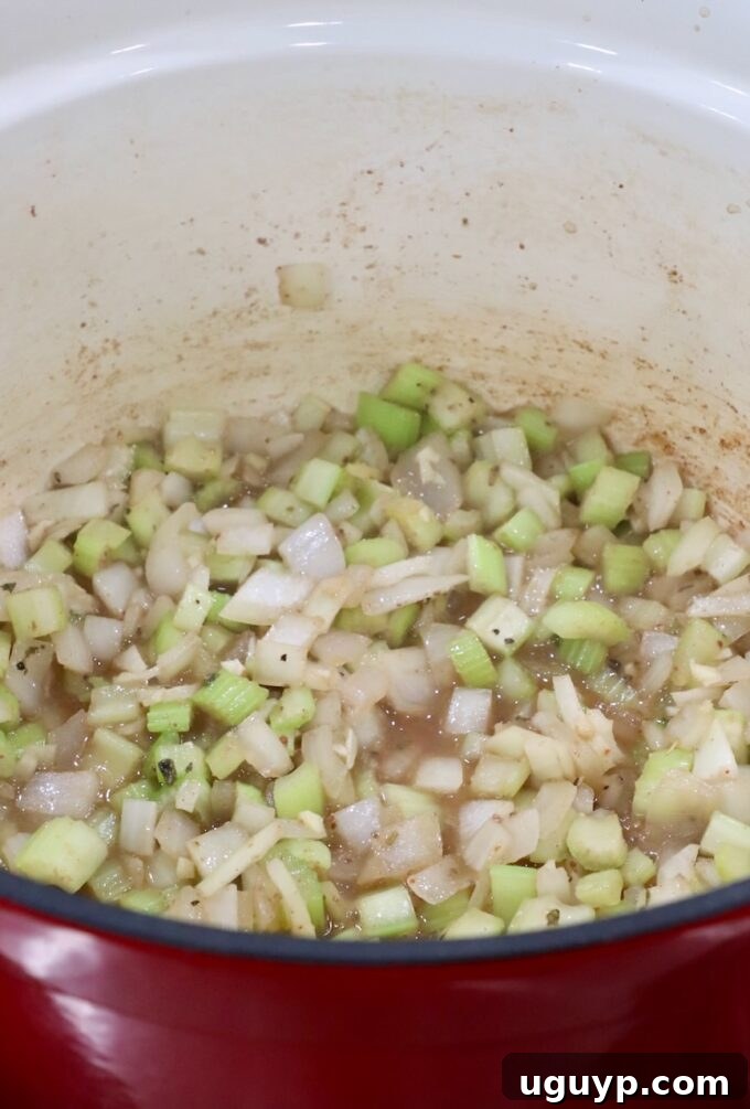 Diced onions and celery in a Dutch oven with beef broth added for deglazing.