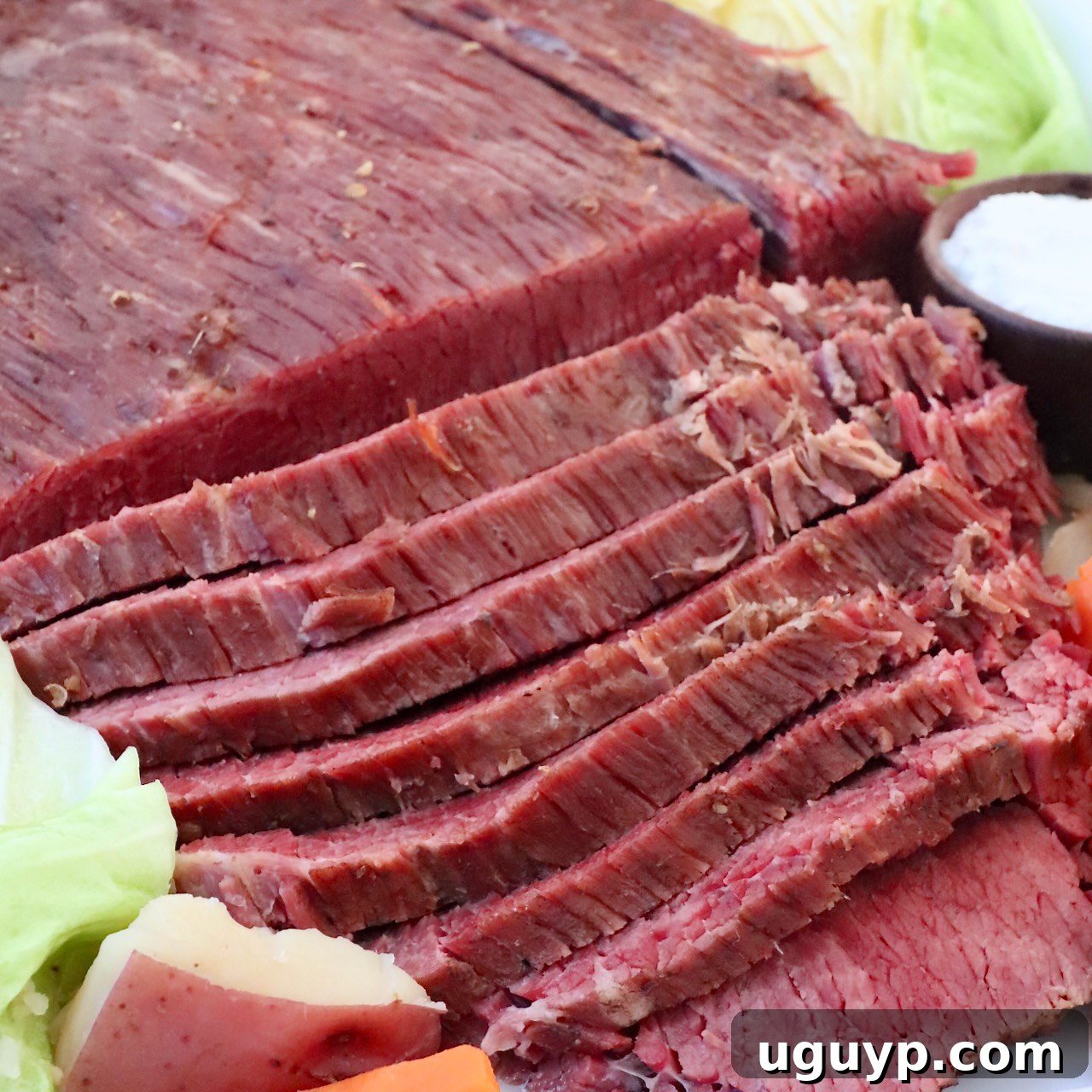 Sliced corned beef on a plate with cabbage, potatoes, and carrots