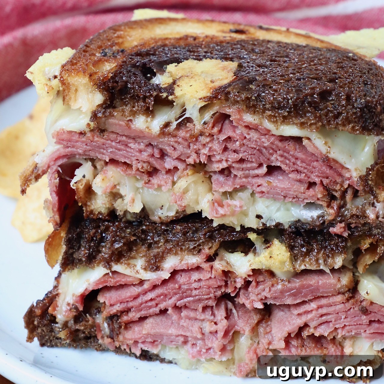 Pastrami Reuben sandwich cut in half and stacked up on a plate