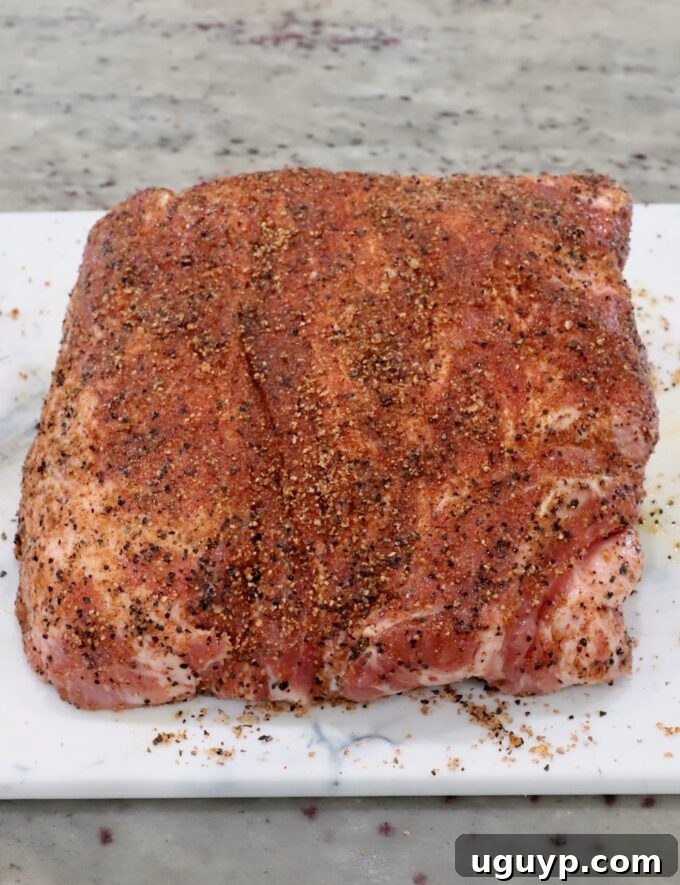 A seasoned pork shoulder covered in a spice rub on a cutting board, ready for cooking.