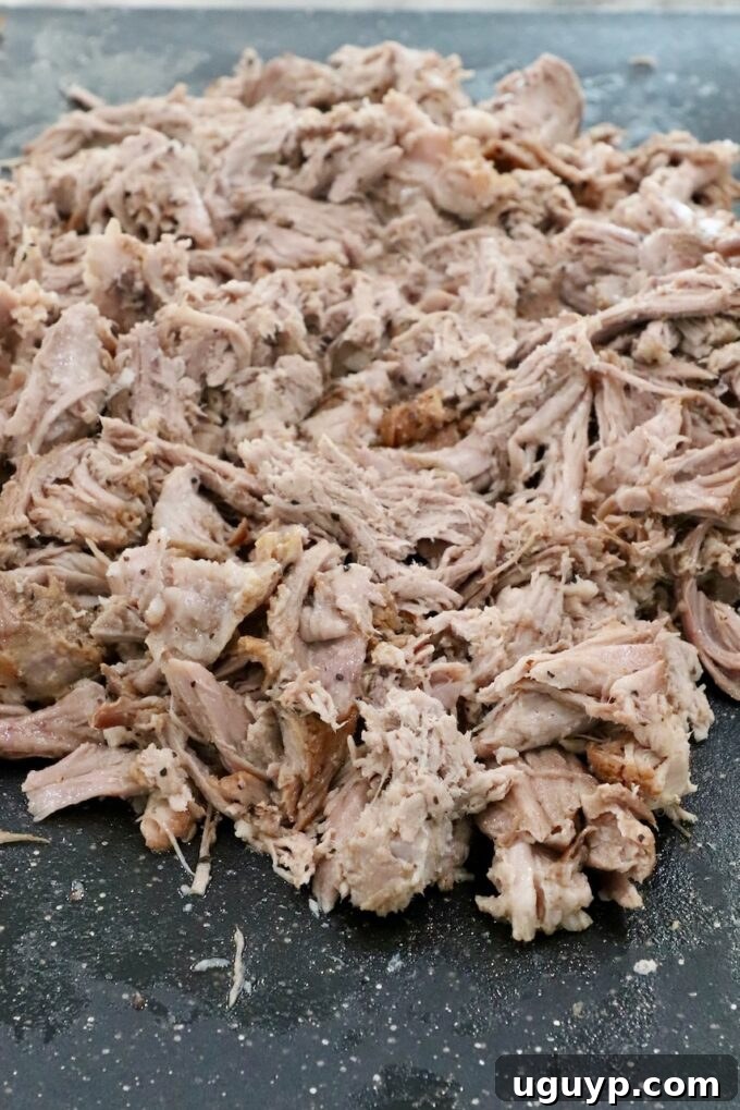 Perfectly shredded pulled pork piled on a cutting board, moist and tender.
