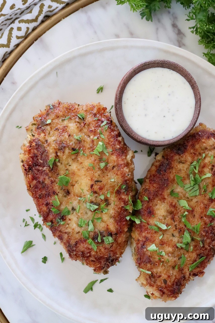 Crispy pan-fried breaded pork chops served on a plate with a side of ranch dressing for dipping.