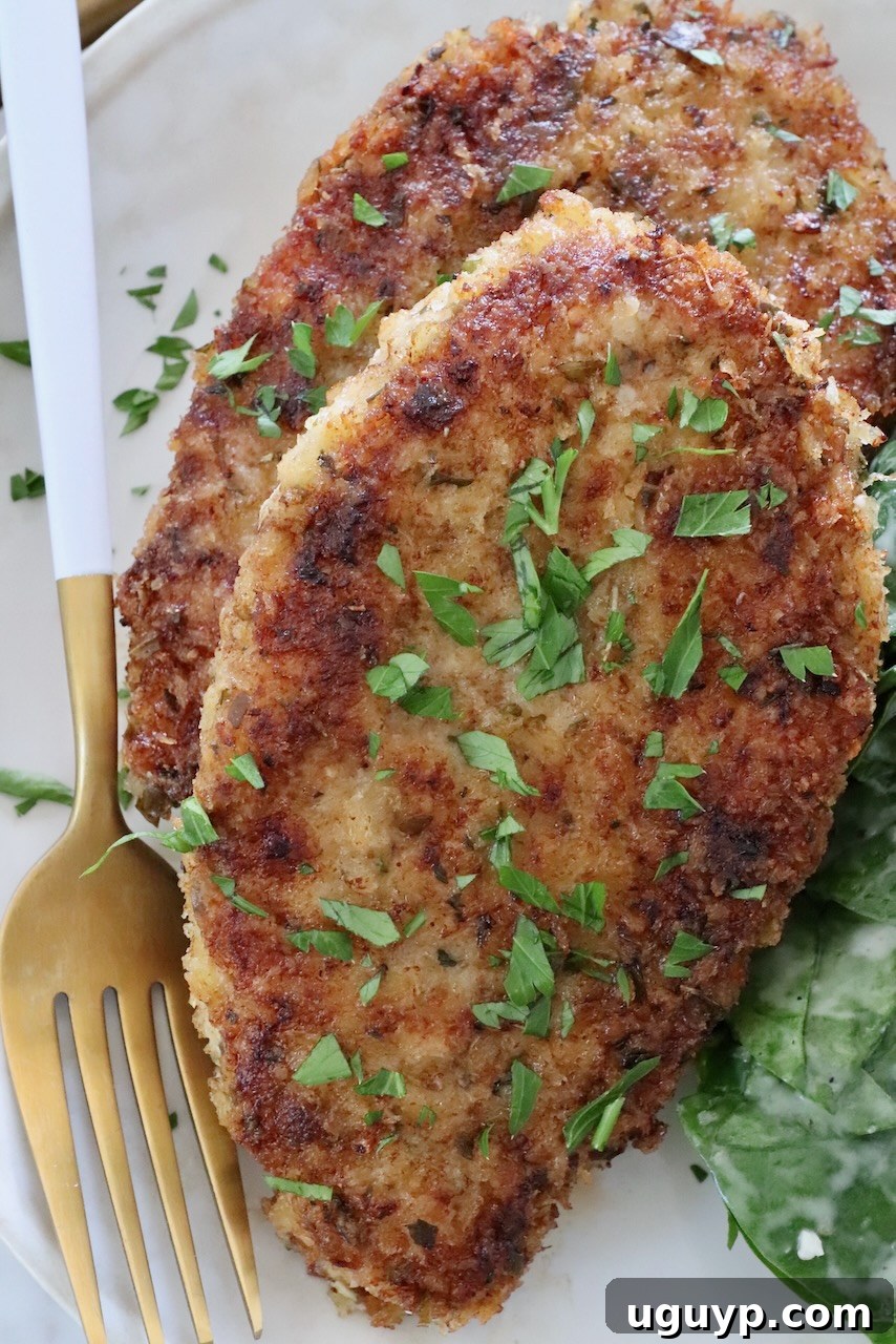 A perfectly cooked, crispy pan-fried breaded pork chop on a plate with a fork, ready to be enjoyed.