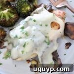 chicken covered in mushrooms and cheese on a plate with broccoli