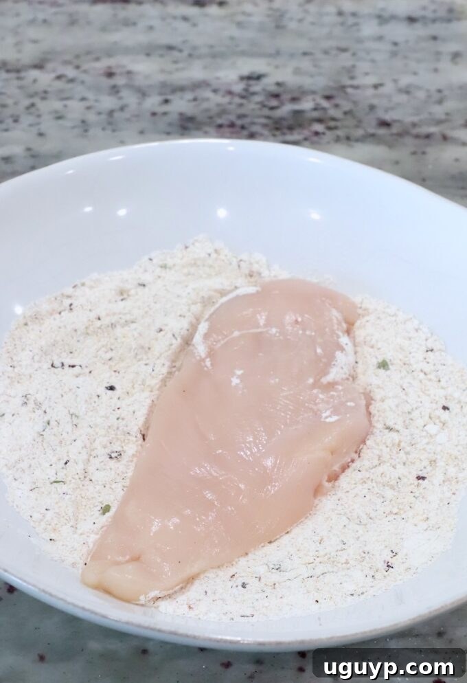 a chicken breast in a bowl of seasoned flour