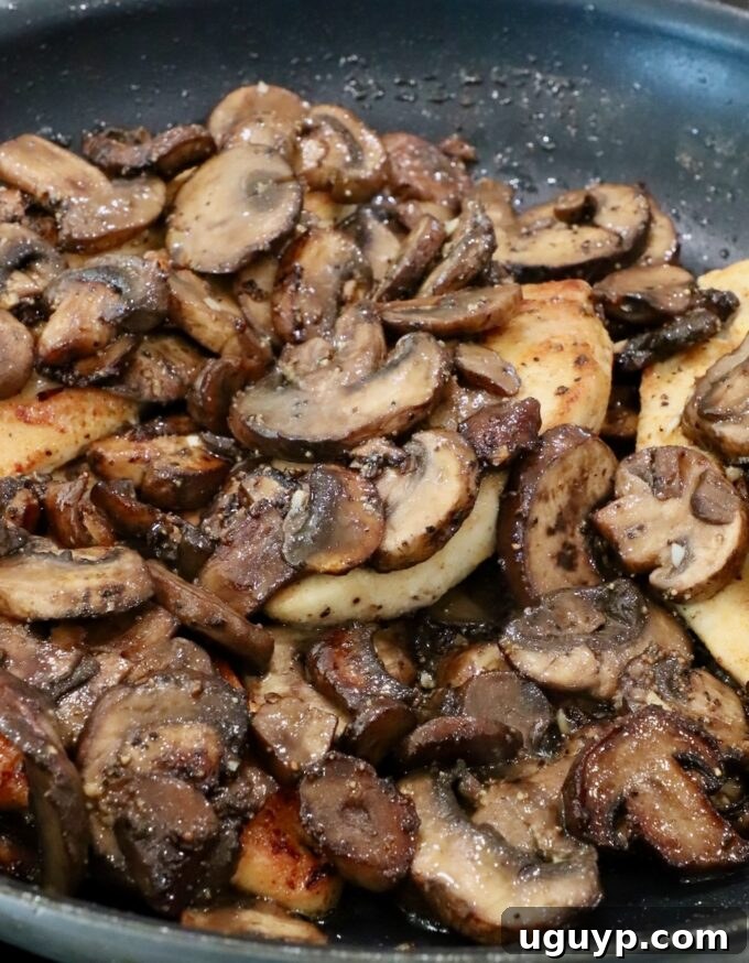 sauteed mushrooms on top of chicken breasts in a skillet