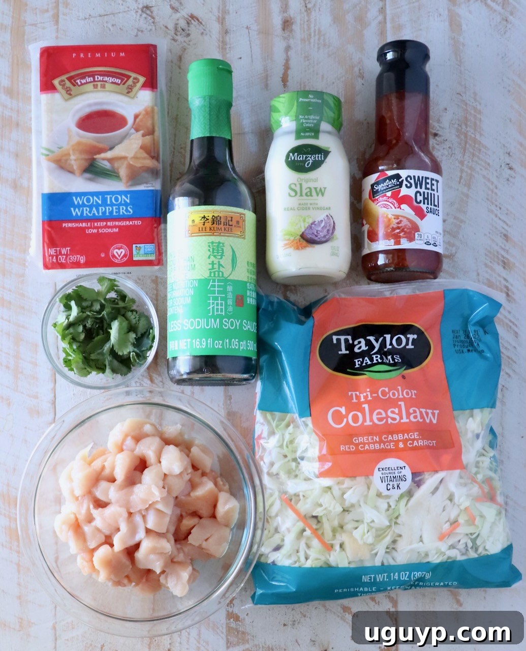 ingredients for chicken wonton tacos on a white wood board