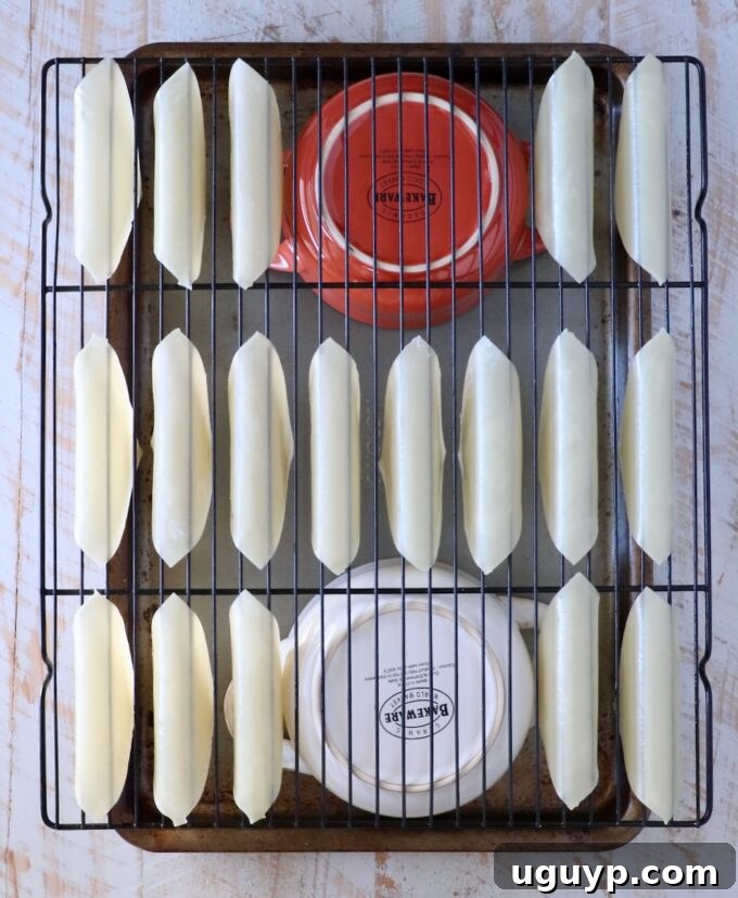 wonton wrappers folder over a wire rack, on top of two bowls on a baking sheet