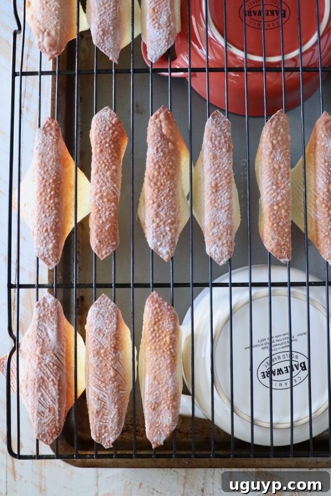 baked wonton wrappers folder over a wire rack, on top of two bowls on a baking sheet