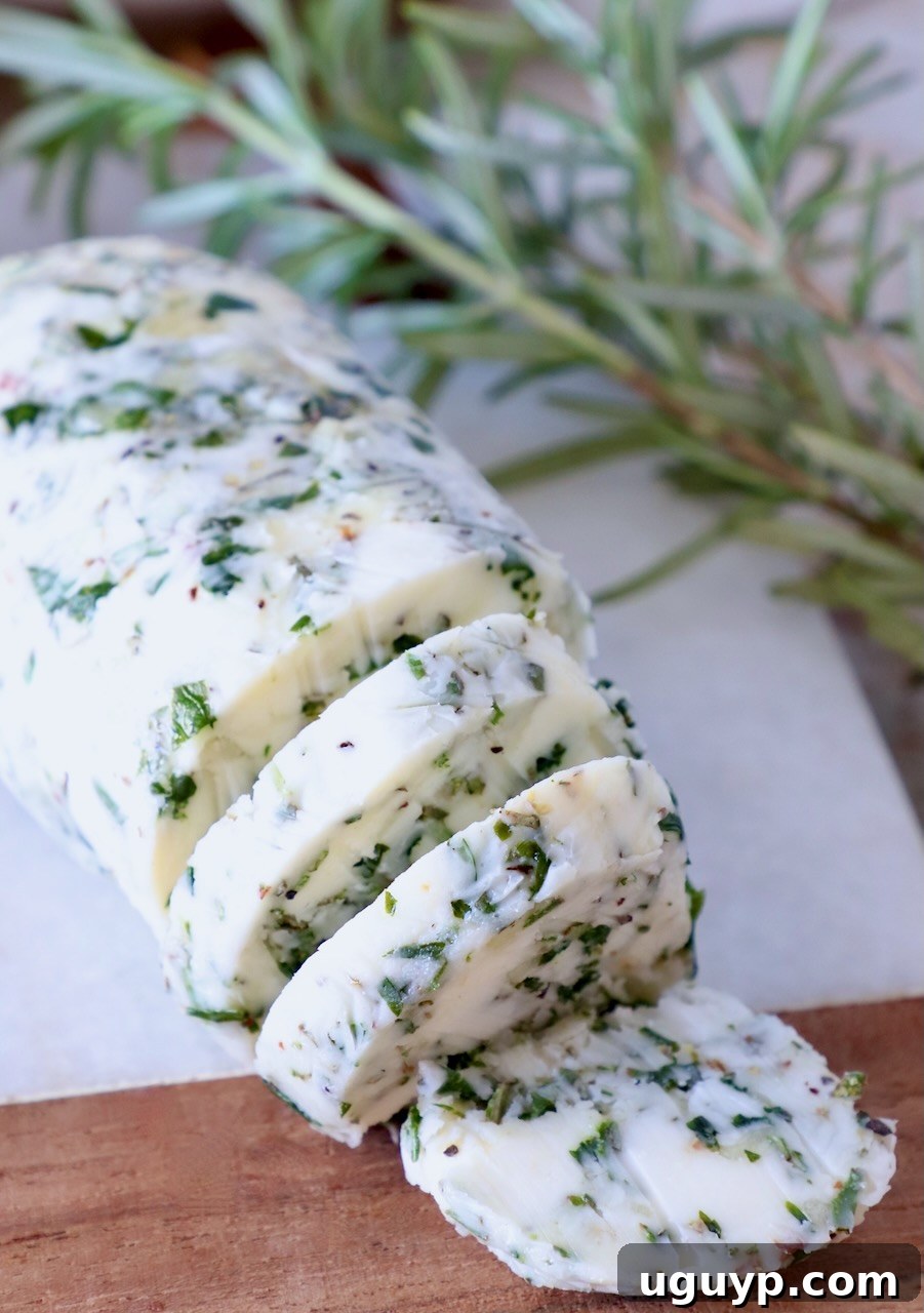 compound butter sliced on a cutting board with fresh rosemary on the side