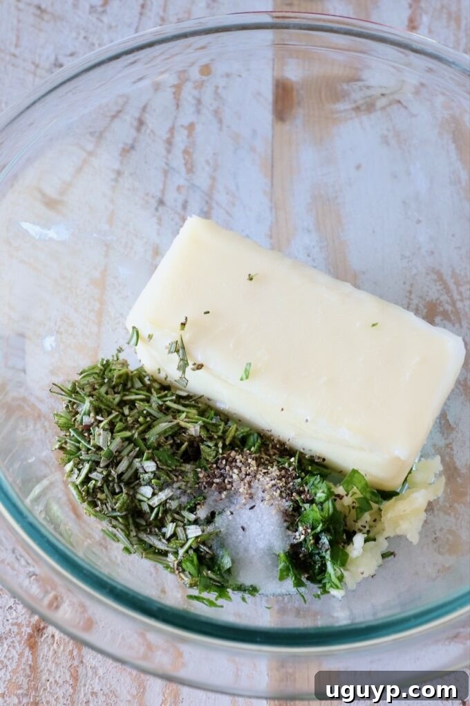 a stick of butter in a glass bowl with herbs, garlic and salt