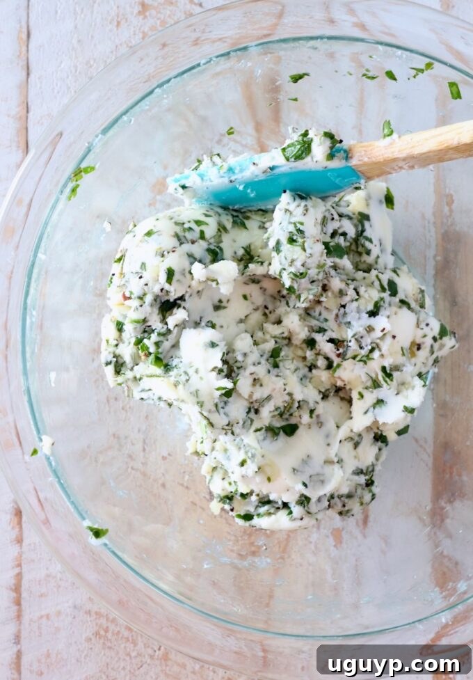 garlic herb compound butter mixed together in a glass bowl with a spatula