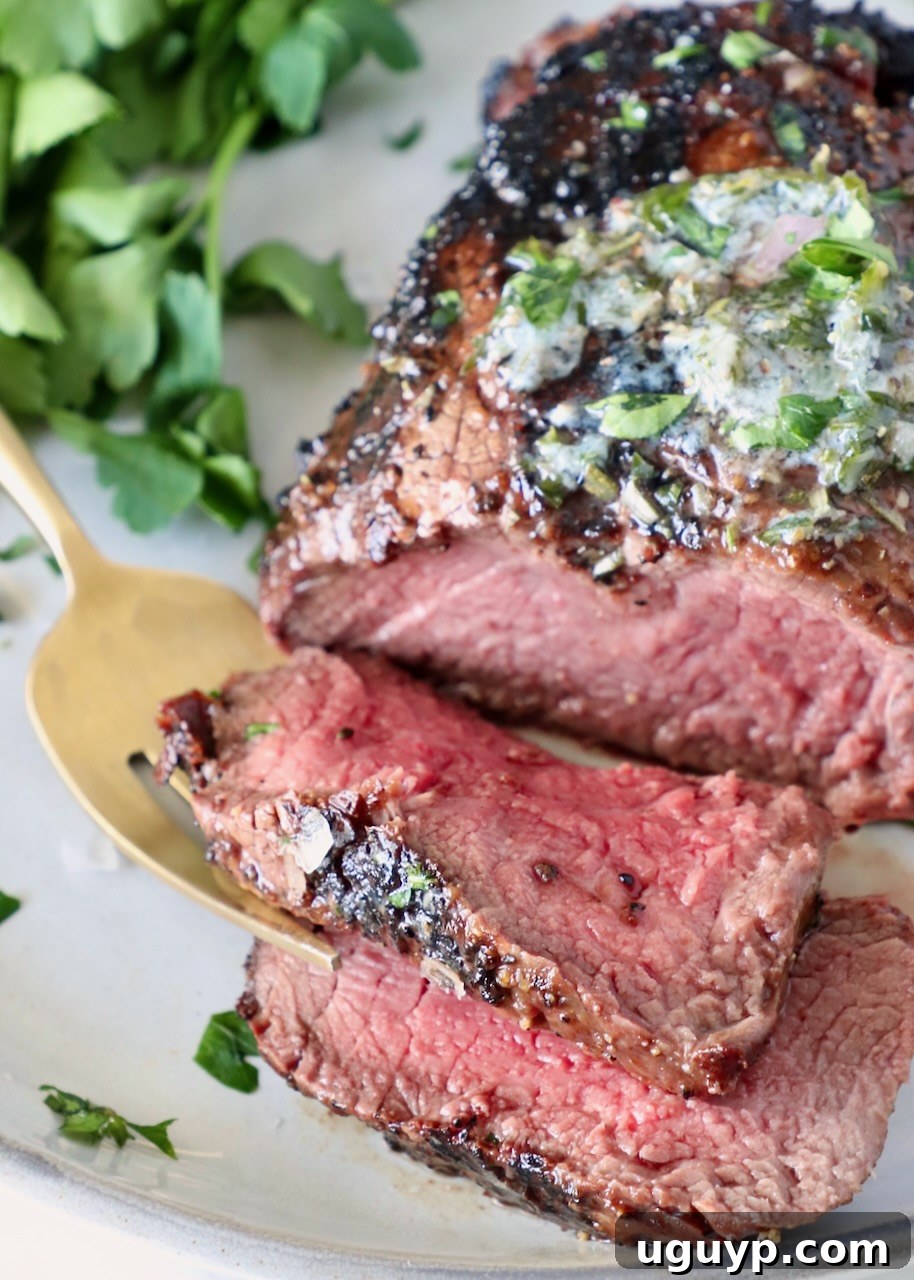 Close-up of a perfectly sliced filet mignon steak on a plate, garnished with fresh parsley and a fork.