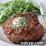 Cooked filet mignon on a plate with herb butter on top