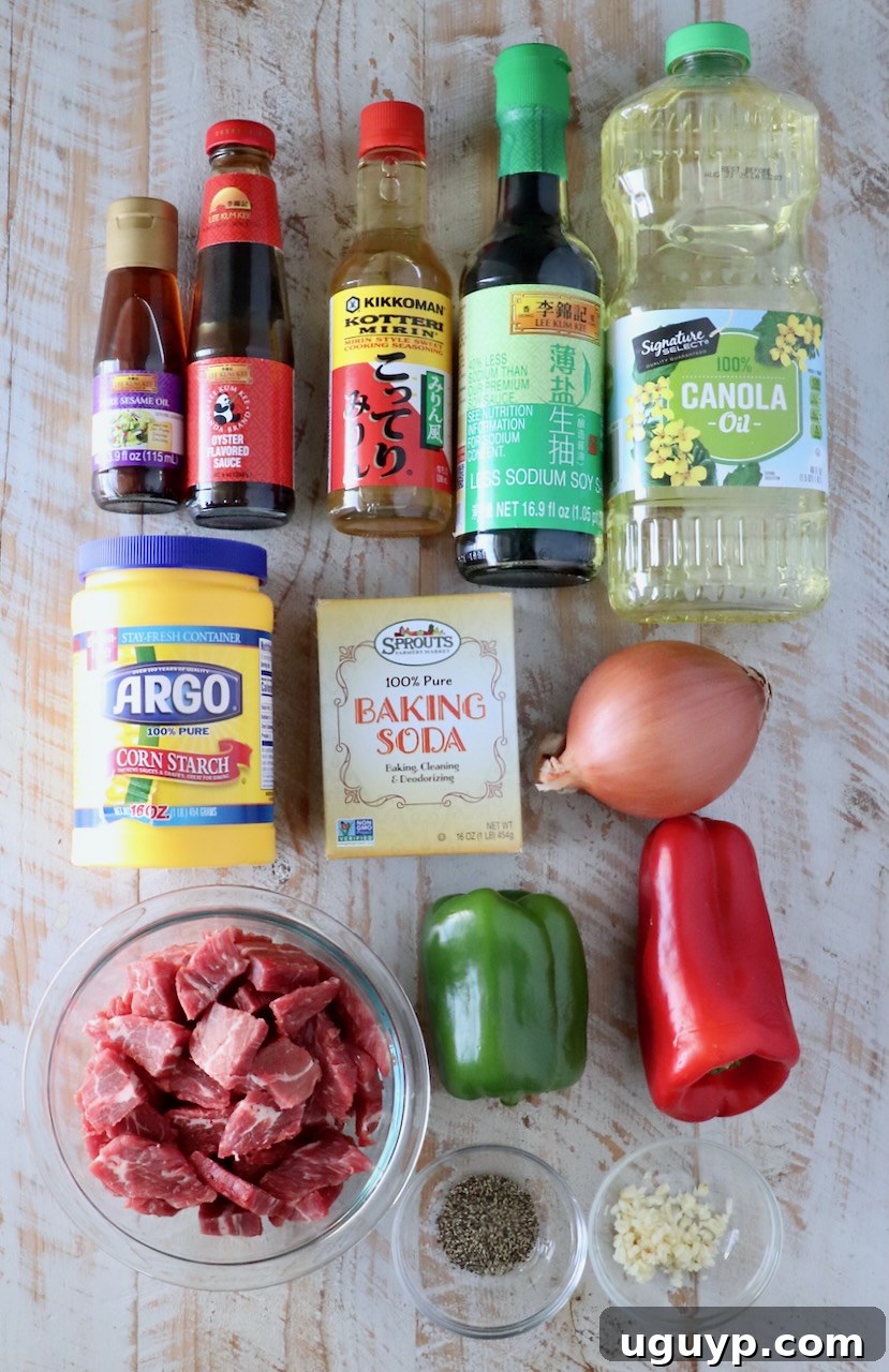 A selection of fresh ingredients for Chinese Pepper Steak, including bell peppers, onions, flank steak, sauces, and oils, neatly arranged on a white wooden board.