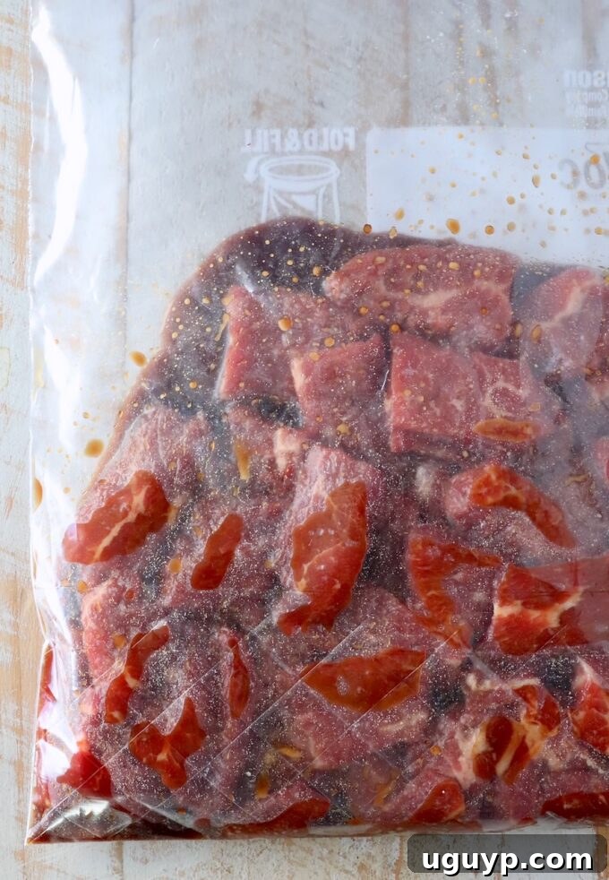 Slices of flank steak marinating in a plastic zipper bag with velveting ingredients, ready for tenderizing.