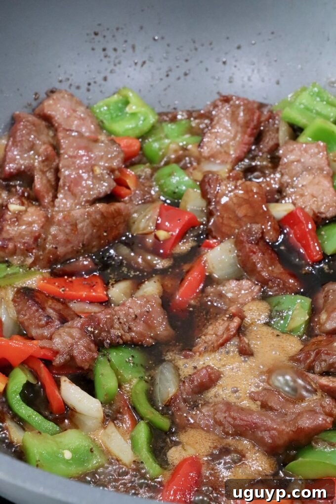 Chinese Pepper Steak stir-fry coated in a glossy black pepper sauce, with tender beef and crisp vegetables, fresh off the stove.