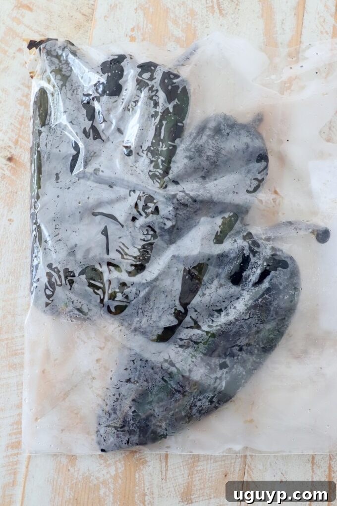 Hot roasted poblano peppers sealed in a plastic zipper bag to steam, which aids in easily peeling their skins.