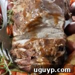 roasted pork on a serving platter with vegetables and rosemary