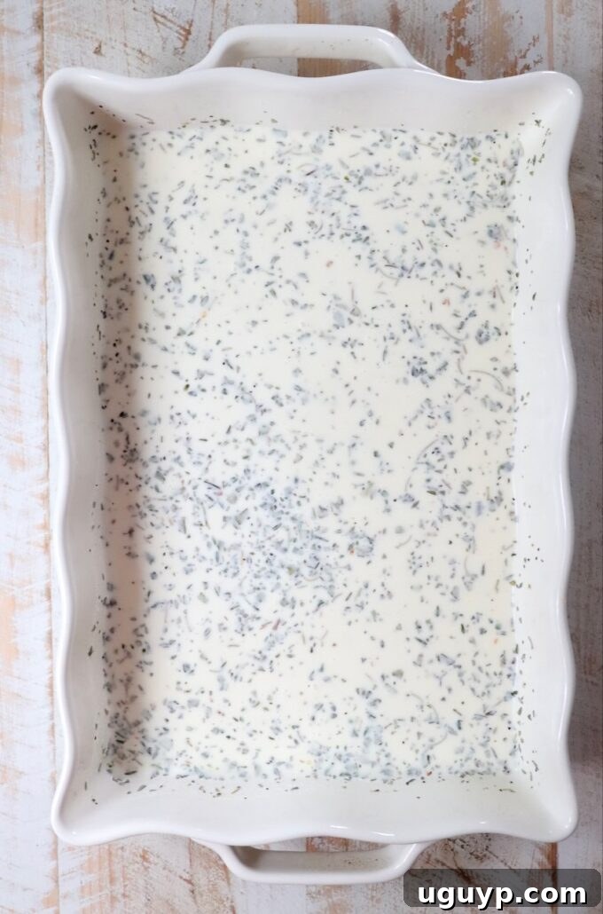 creamy seasoned sauce being whisked in a casserole dish
