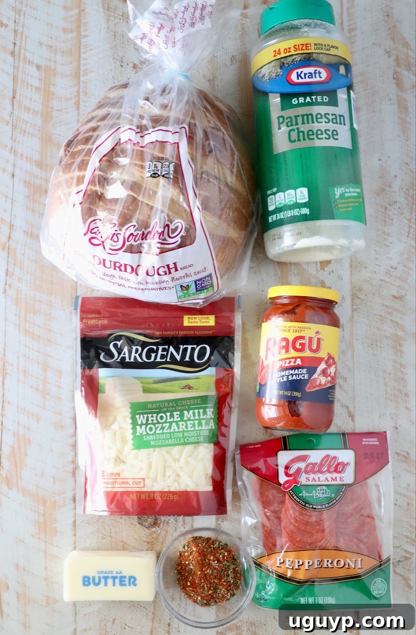 A collection of fresh ingredients for Pizza Grilled Cheese neatly arranged on a rustic white wooden board, including sourdough bread, softened butter, parmesan cheese, pizza seasoning, pizza sauce, mozzarella cheese, and pepperoni slices.