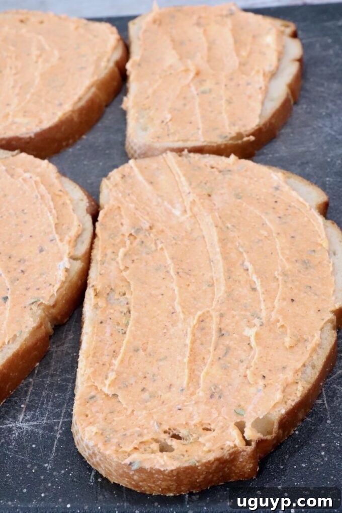 Thick slices of sourdough bread spread generously with the savory pizza butter mixture, placed on a wooden cutting board, prepped for grilling.