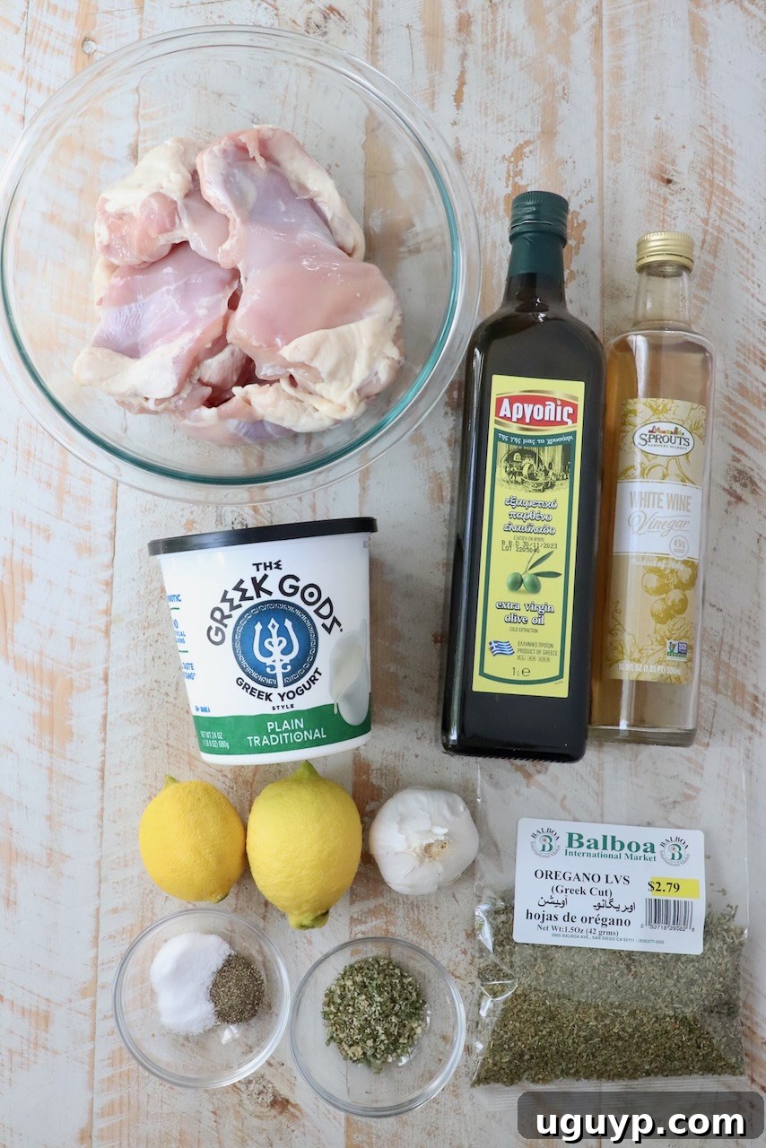 A beautiful flat lay photograph showcasing all the fresh ingredients needed to prepare a mouthwatering Greek chicken gyro, neatly arranged on a rustic white wooden board.