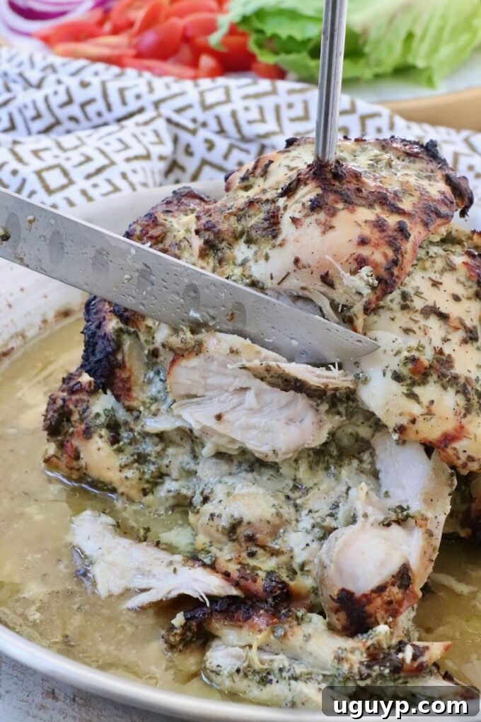 A sharp knife expertly slicing thin, tender pieces of roasted chicken from a vertical skewer, showcasing the succulent texture of the gyro meat.