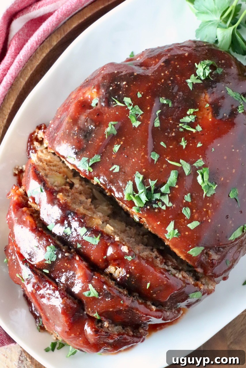 partially sliced cooked and glazed meatloaf on a white plate
