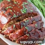 glazed, cooked meatloaf partially sliced on a plate