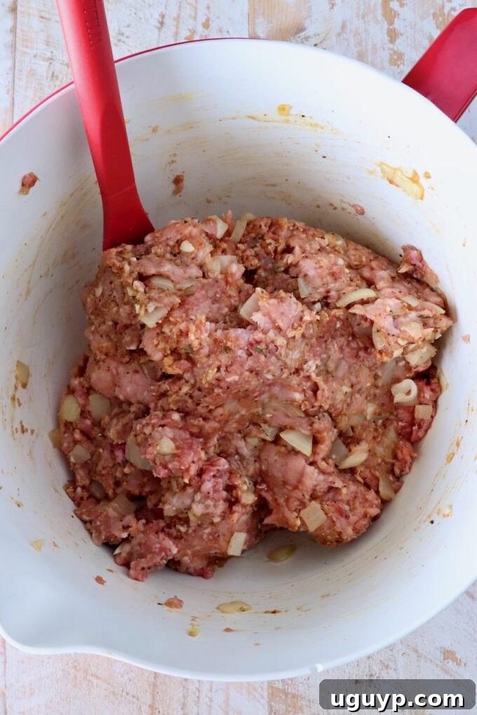 meatloaf mixture combined in a mixing bowl with a red spatula