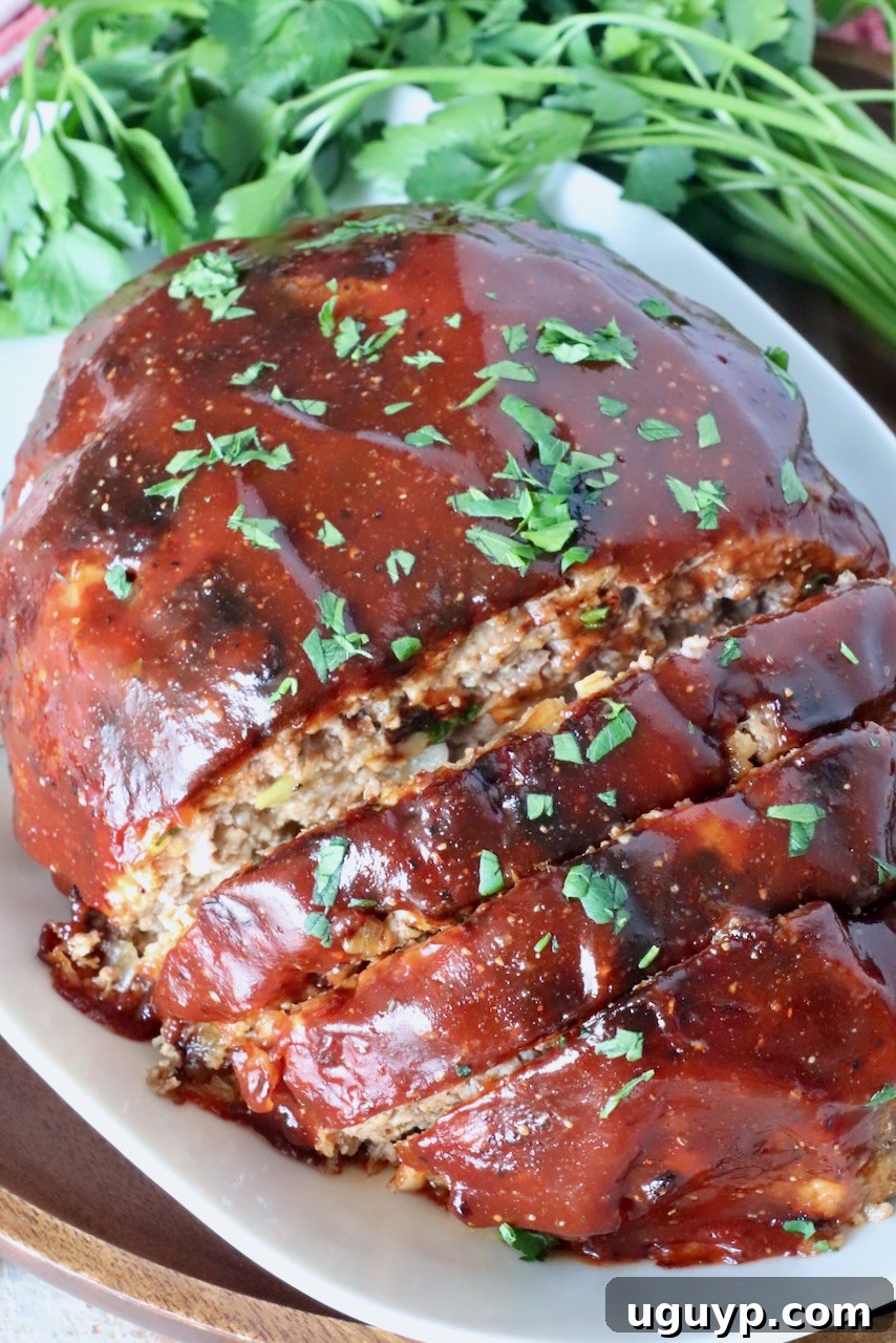 glazed cooked meatloaf sliced on a plate with fresh parsley