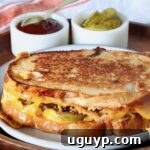 A delicious meatloaf sandwich presented on a plate, with small bowls of BBQ sauce and pickles visible in the background.