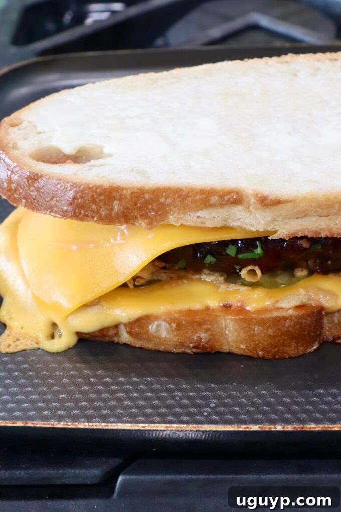 A meatloaf sandwich cooking on a griddle pan on the stove, showing one side toasted golden brown.