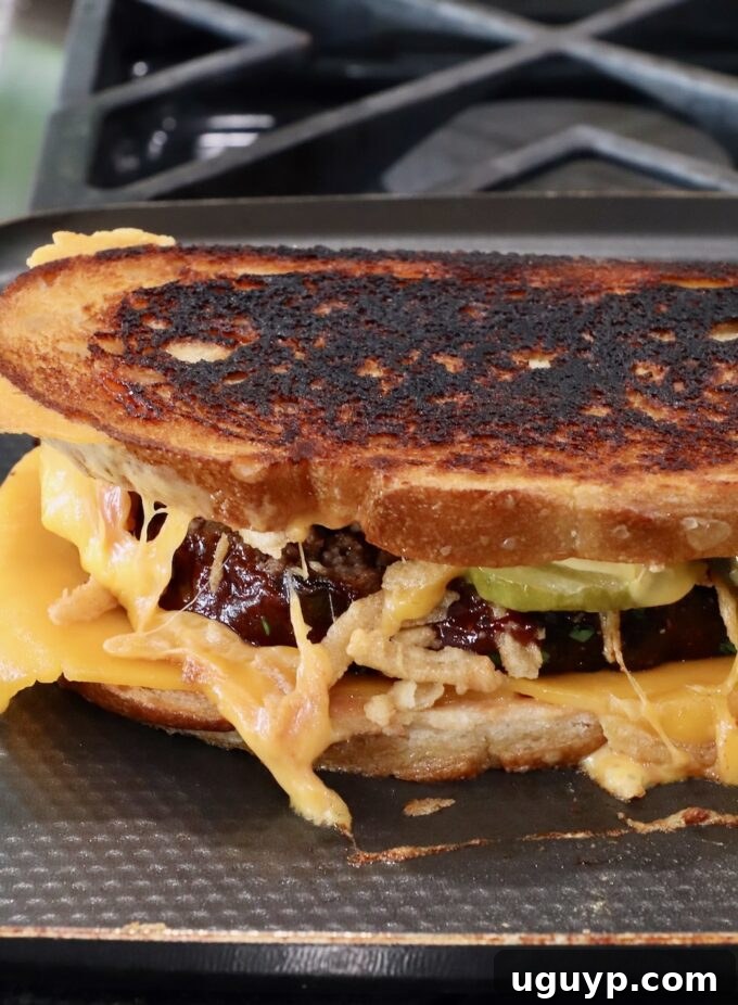 A cooked meatloaf sandwich, beautifully golden and toasted, still on the griddle pan.