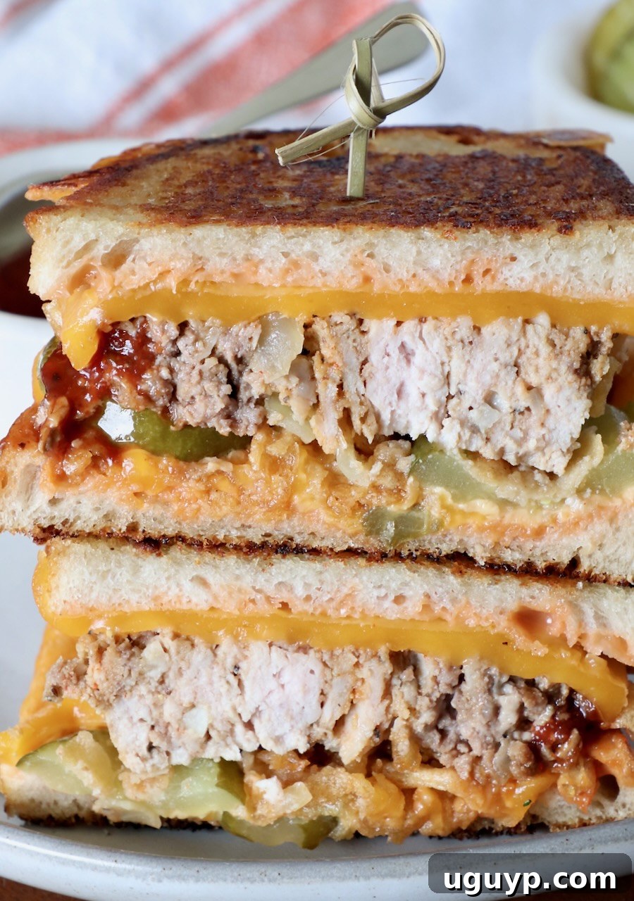 A meatloaf sandwich, sliced in half and stacked, with a wooden skewer, on a plate. It is perfectly toasted with melted cheese and visible fillings.