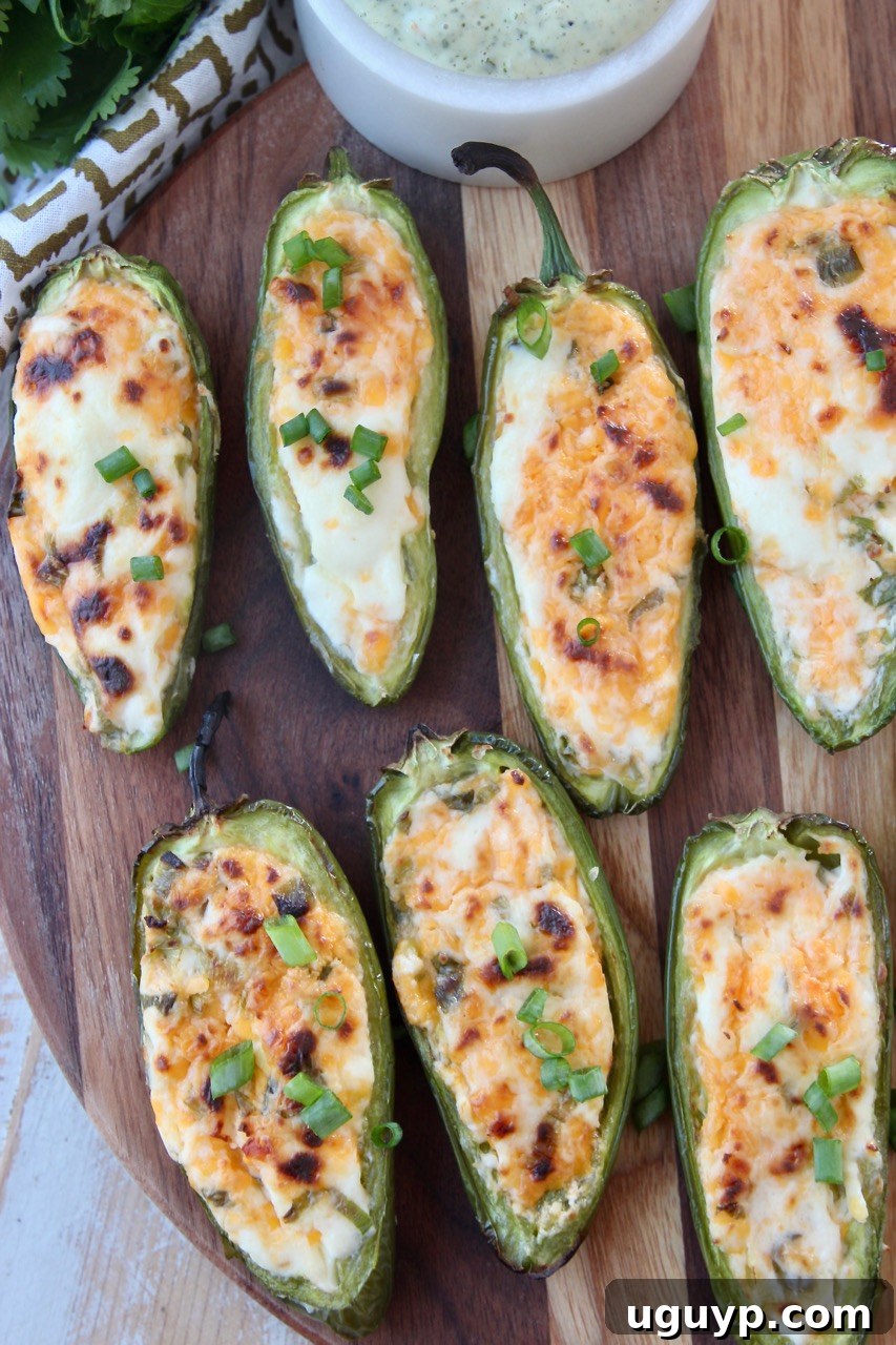 Grilled jalapeno poppers on a wood cutting board, garnished with fresh herbs
