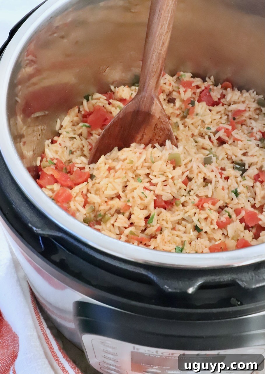 cooked Mexican rice in an Instant Pot with a large wooden spoon, garnished with fresh cilantro