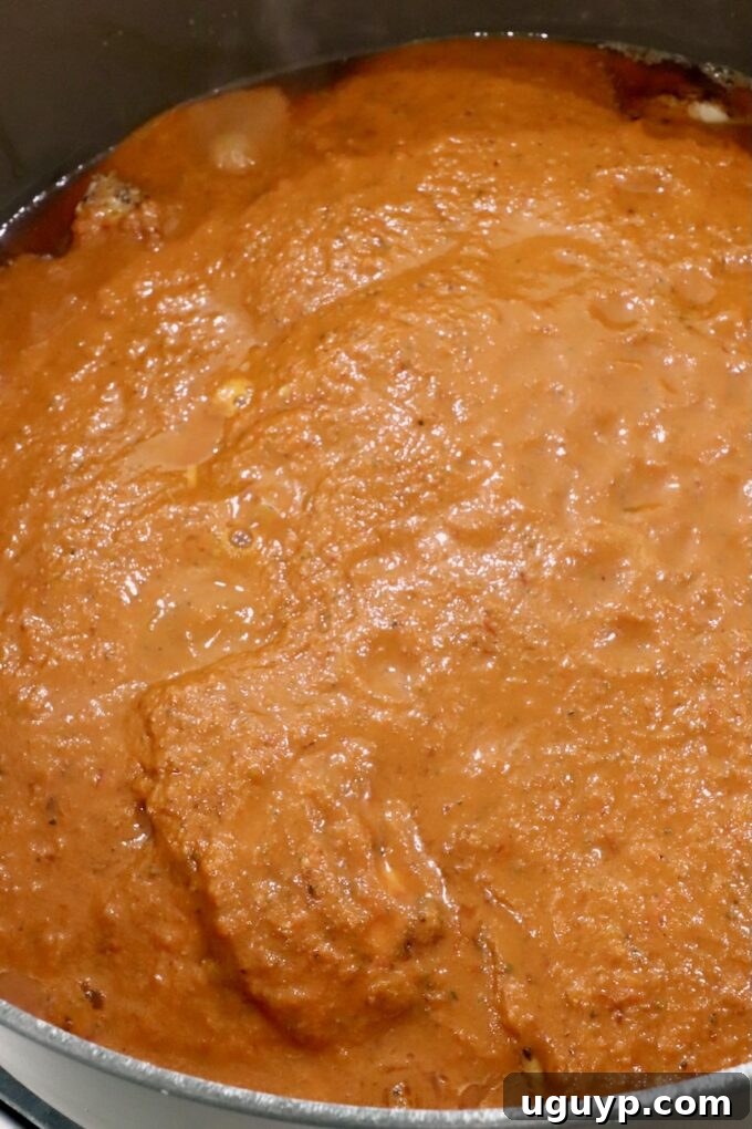 Cooked chicken thighs lovingly covered in the vibrant adobo sauce within a large Dutch oven, ready for simmering.