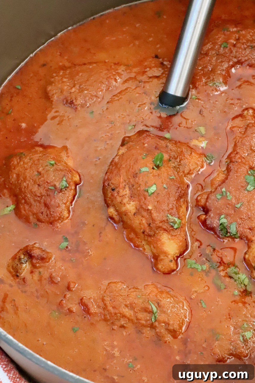 Chicken covered in adobo sauce in a large pot with a serving spoon, ready to be served.