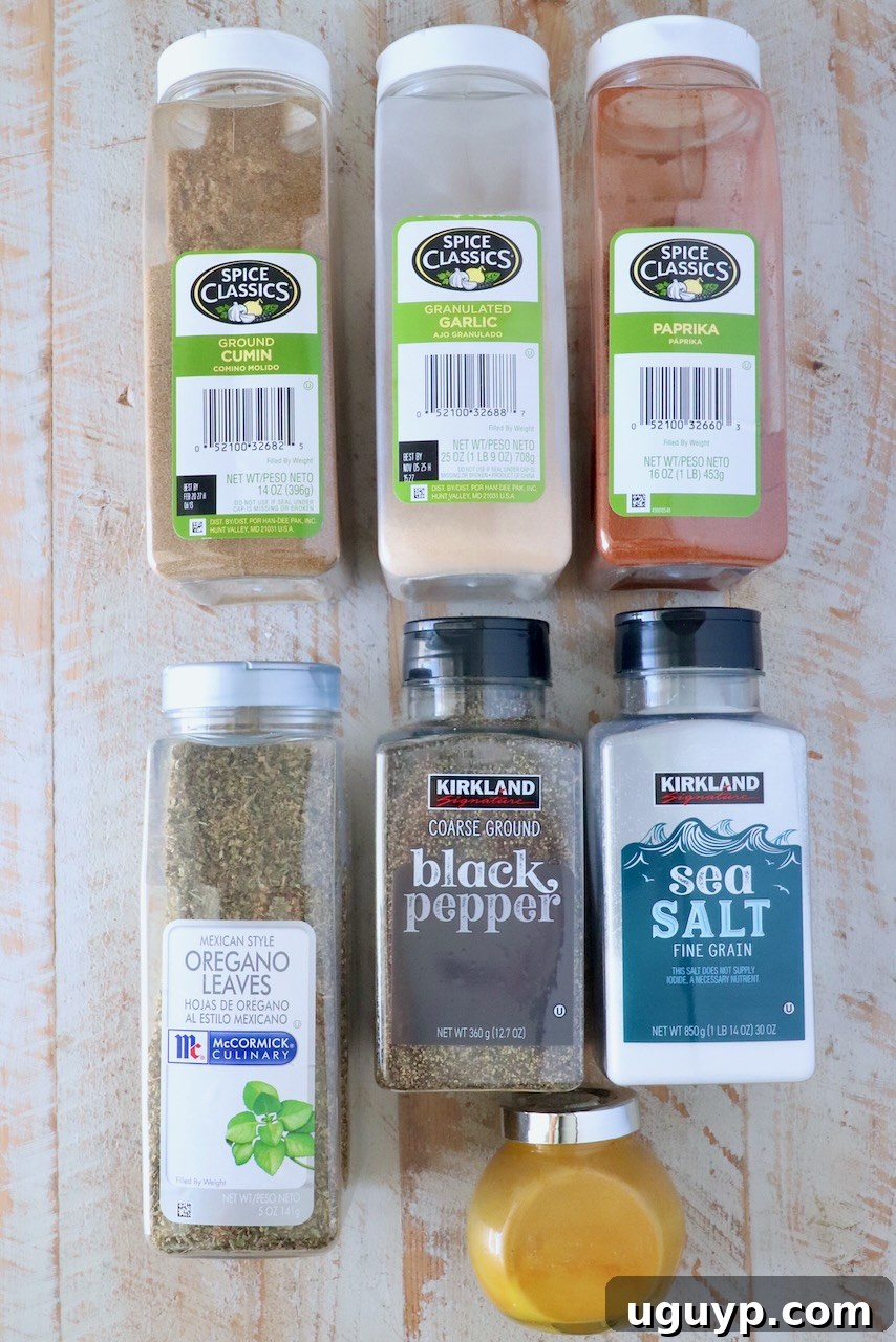 containers of spices lined up on a white wood board, illustrating the fresh ingredients used in homemade seasoning