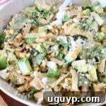 A close-up of Mexican street corn salad in a bowl with a fork, showing the creamy dressing and fresh ingredients