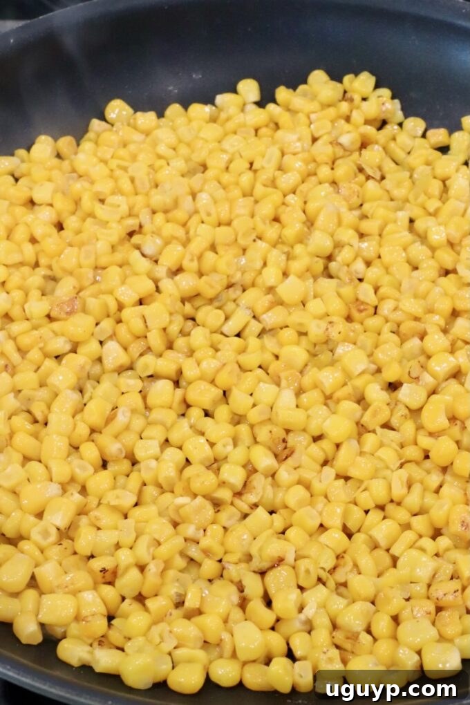 Charred corn kernels sizzling in a hot skillet