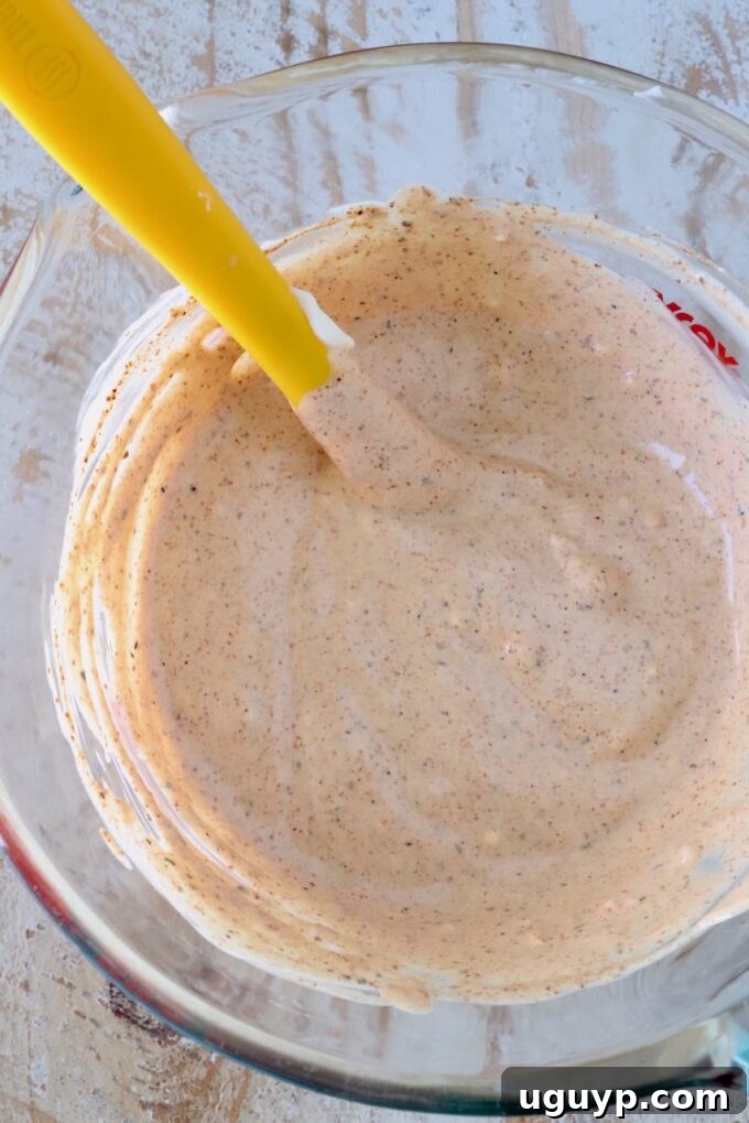 Creamy chili lime dressing in a glass bowl with a yellow spatula, ready to be mixed