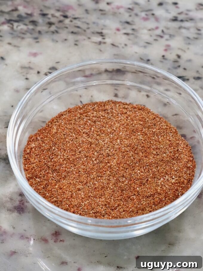 Small glass bowl containing a blend of chipotle chili powder, cumin, paprika, garlic powder, and salt for seasoning chicken.