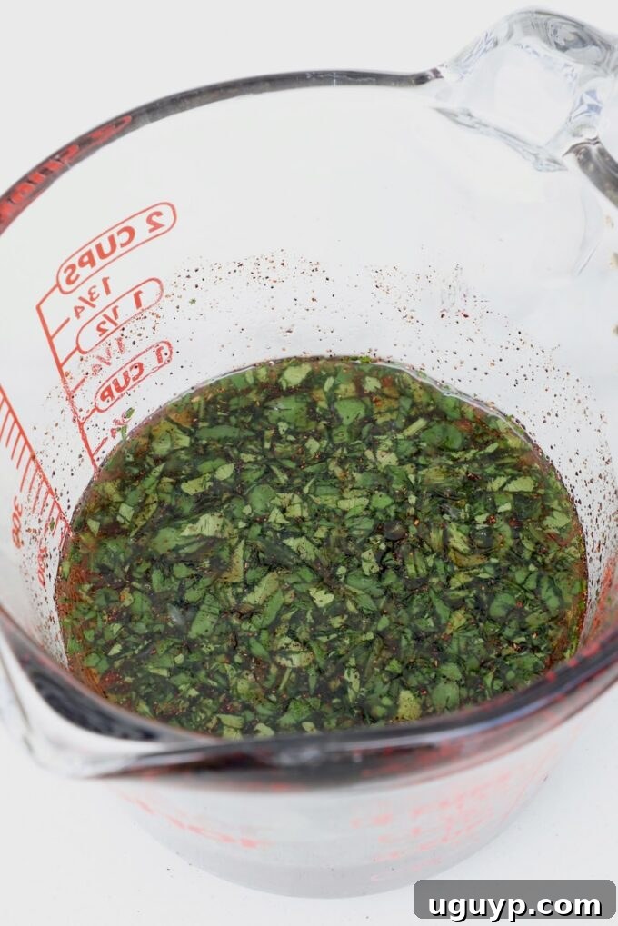 Glass measuring cup filled with a golden honey glaze, mixed with fresh cilantro, lime juice, and a hint of chipotle chili powder.