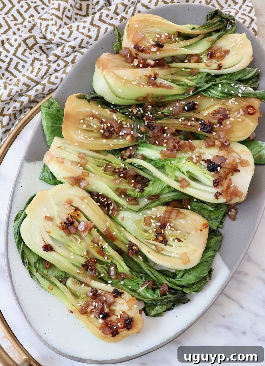 A large serving platter piled high with perfectly cooked, glistening sautéed baby bok choy, ready to be enjoyed as a healthy side dish.
